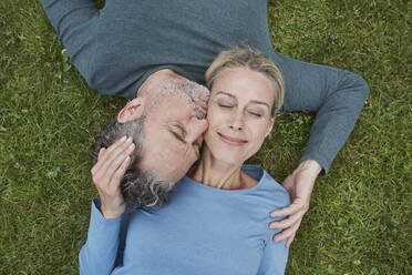 Top view of affectionate mature couple lying in grass - RORF01929
