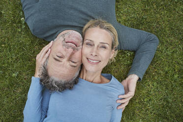 Draufsicht auf ein glückliches reifes Paar im Gras liegend - RORF01930