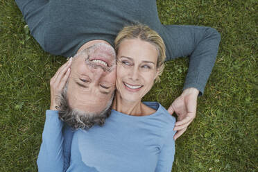 Top view of happy mature couple lying in grass - RORF01932