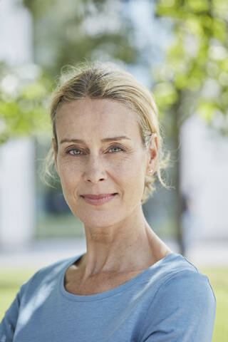 Portrait of confident blond woman in a park stock photo