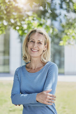 Porträt einer lächelnden blonden Frau in einem Park, lizenzfreies Stockfoto