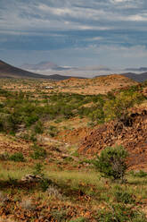 Farbenfrohe Felsenlandschaft hoch oben in den Bergen, mit Bergcamp im Hintergrund, Etendeka, Namibia, Afrika - RHPLF10313