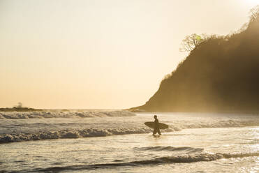 Surfers surfing on a beach at sunset, Nosara, Guanacaste Province, Pacific Coast, Costa Rica, Central America - RHPLF10358