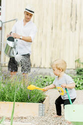 Vater mit kleinem Jungen bei der Arbeit im Garten - JOHF00506