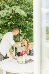 Parents with baby boy resting on balcony - JOHF00512