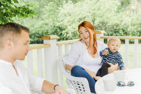 Parents with baby boy resting on balcony - JOHF00513