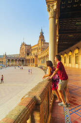 Ein Touristenpaar bewundert den Platz von der verzierten Säulenhalle aus, Plaza de Espana, Sevilla, Andalusien, Spanien, Europa - RHPLF10791