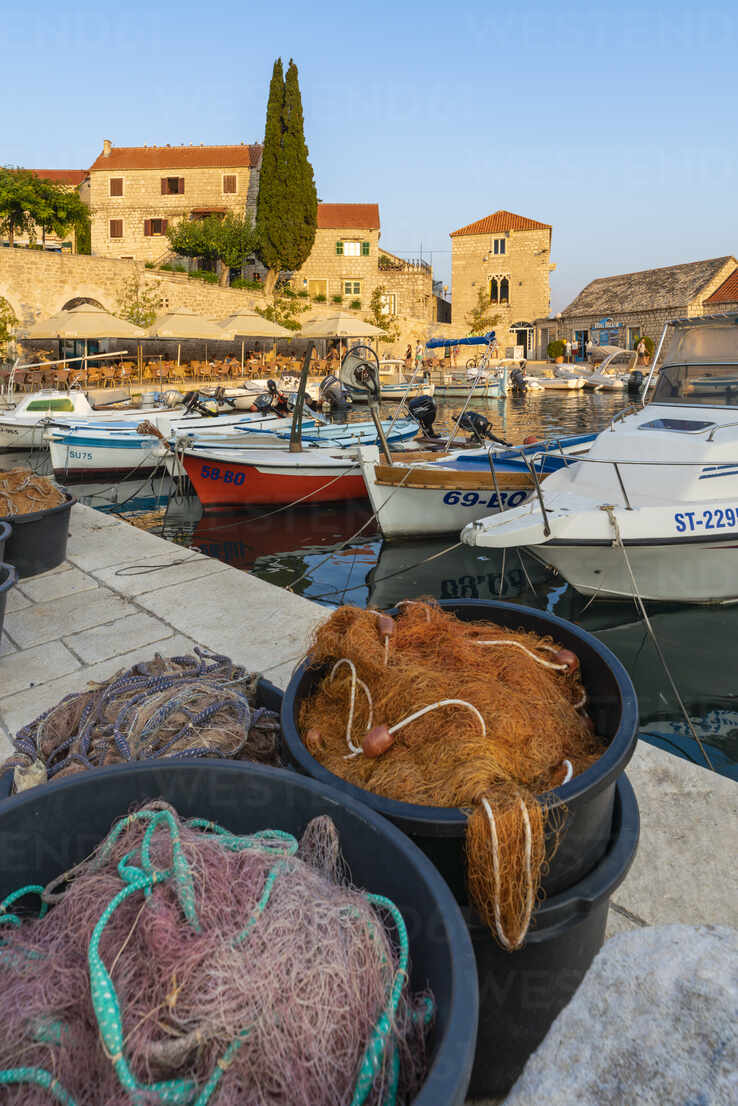 Boats and fishing nets at the pier of the town at sunset, Bol, Brac island,  Split-Dalmatia county, Croatia, Europe stock photo