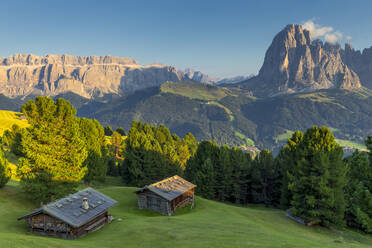 Letzte Sonnenstrahlen auf traditionellen Hütten mit Blick auf Langkofel und Sellagruppe, Grödnertal, Südtirol, Dolomiten, Italien, Europa - RHPLF10898