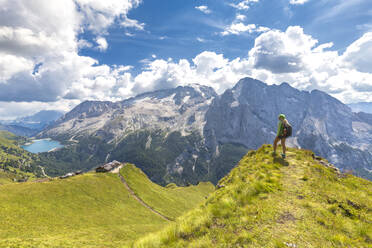 Hiker looks towards Viel del Pan Refuge with Marmolada in the background, Pordoi Pass, Fassa Valley, Trentino, Dolomites, Italy, Europe - RHPLF10922