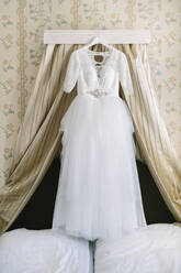 Hochzeitskleid über dem Bett hängend - JOHF00690