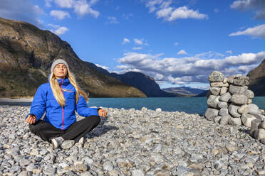 Woman meditating at riverside - JOHF00789