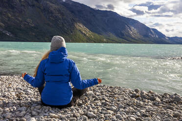 Woman meditating at riverside - JOHF00791