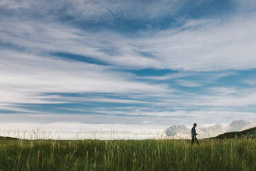 Hiker walking through meadow - JOHF00871