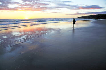 A woman walks on Southerndown beach, Ogmore, South Wales, United Kingdom, Europe - RHPLF10959