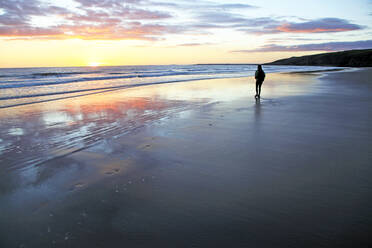 Eine Frau spaziert am Strand von Southerndown, Ogmore, Südwales, Vereinigtes Königreich, Europa - RHPLF10959