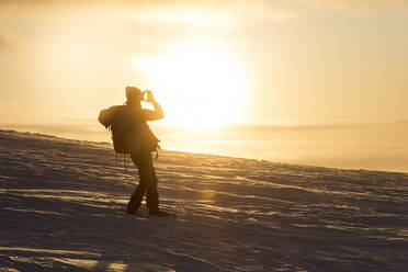 Fotograf bei Sonnenuntergang, Pallas-Yllastunturi-Nationalpark, Muonio, Lappland, Finnland, Europa - RHPLF10988