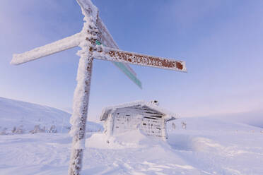 Gefrorene Beschilderung und Holzhütte, Pallas-Yllastunturi-Nationalpark, Muonio, Lappland, Finnland, Europa - RHPLF10990