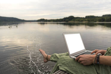 Junge Frau mit Laptop auf einem Steg an einem See - JOSF03609