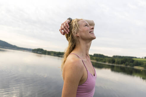 Happy young woman at a lake - JOSF03616