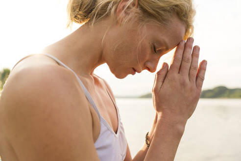 Close-up of young woman with closed eyes at a lake - JOSF03633