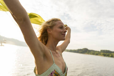 Young woman holding a cloth at a lake - JOSF03642