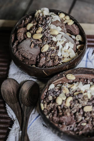 Nahaufnahme von Schokoladeneis mit Früchten und Nüssen, serviert in Schalen auf einem Tisch, lizenzfreies Stockfoto