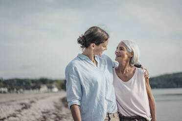 Mother and daughter spending a day at the sea, embracing on the beach - JOSF03646