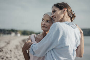 Mother and daughter spending a day at the sea, embracing on the beach - JOSF03647