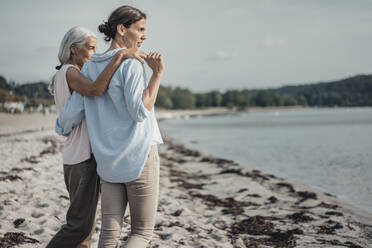 Mother and daughter spending a day at the sea, embracing on the beach - JOSF03650