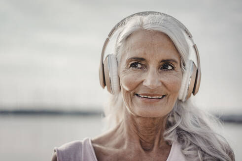 Ältere Frau hört Musik mit Kopfhörern am Meer, Poartrait - JOSF03662