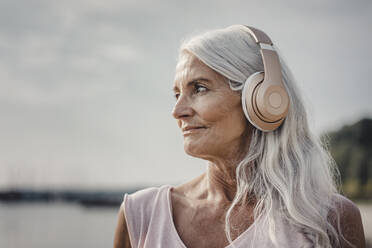 Ältere Frau hört Musik mit Kopfhörern am Meer, Poartrait - JOSF03663