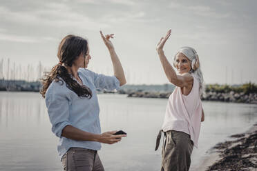 Mother and daughter spending a day at the sea, listening music - JOSF03664