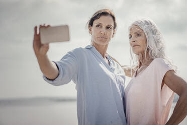 Mother and daughter spending a day at the sea, takinf´g smartphone selfies - JOSF03686