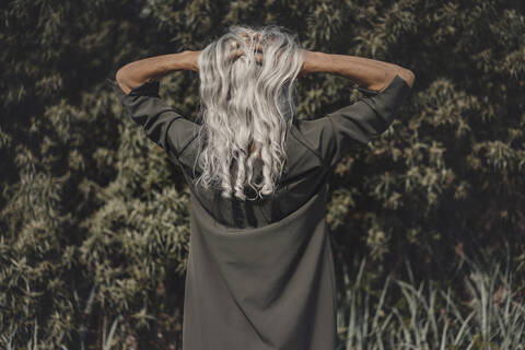 Rückansicht einer älteren Frau mit Händen in ihrem weißen Haar, lizenzfreies Stockfoto