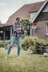 Woman playing diadolo in her garden - JOSF03732