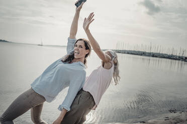 Mother and daughter spending a day at the sea, dancing, listening music - JOSF03738