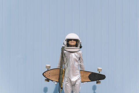 Kind als Astronaut verkleidet mit Longboard, lizenzfreies Stockfoto