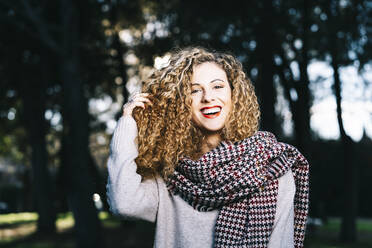 Porträt einer lachenden jungen Frau mit Locken in einem Park - DAMF00051