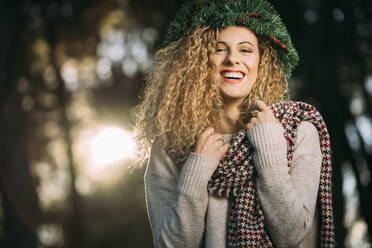 Porträt einer lachenden jungen Frau mit Weihnachtskranz auf dem Kopf - DAMF00054