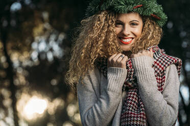 Portrait of young woman wearing Christmas wreath on her head - DAMF00056