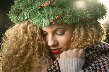 Portrait of smiling young woman wearing Christmas wreath on her head - DAMF00061