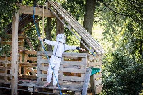 Junge als Superheld, Astronaut, der in einem Baumhaus spielt - HMEF00542