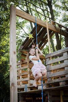 Girl dressed as a princess with crown and sceptre playing in a tree house - HMEF00548