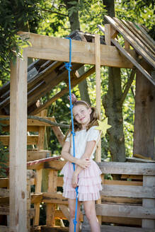 Girl dressed as a princess with crown and sceptre playing in a tree house - HMEF00550