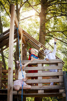 Drei Kinder mit Superhelden-Kostümen spielen in ihrem Baumhaus - HMEF00570