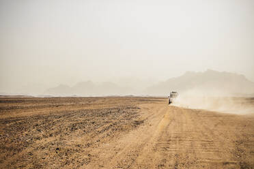Off-road vehicle moving on arid landscape against clear sky, Suez, Egypt - PUF01716