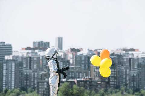 Als Astronaut verkleideter Junge mit Luftballons in der Stadt, lizenzfreies Stockfoto
