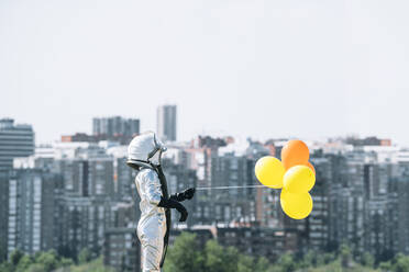 Boy dressed as an astronaut holding balloons in the city - JCMF00208