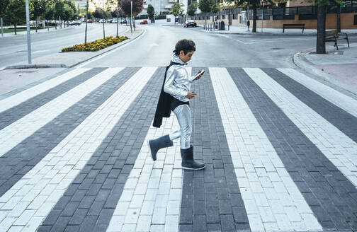 Portrait of boy disguised as superhero crossing a street the city - JCMF00217